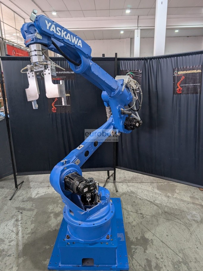 Robot industrial Yaskawa de la serie MH en color azul, equipado con pinza para manipulación de materiales, operando en un entorno de exhibición con paneles oscuros de fondo; diseñado para manejar cargas pesadas con alta precisión y eficiencia en procesos de automatización industrial. ``